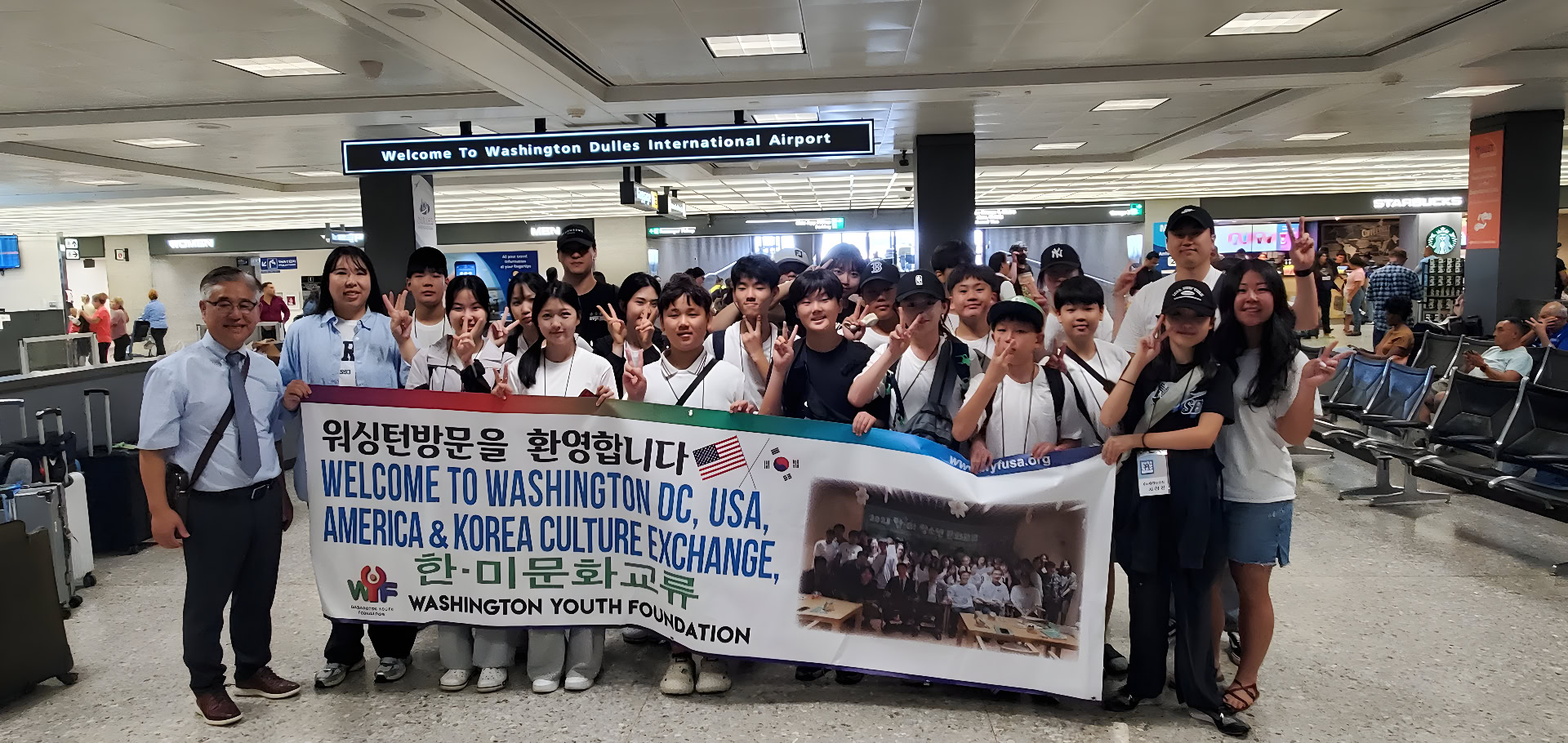 Group_of_people_at_airport_holding_banner.jpg